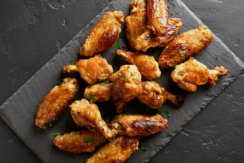 Fire roasted chicken wings on dark slate board